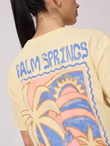 Remera color amarillo claro con estampado en el frente que incluye un sol y el texto 'Rusty Club'. Corte holgado.