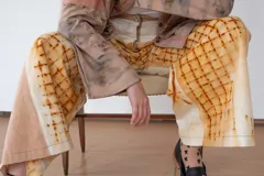 Pantalón de algodón color crudo con estampado de óxidos naturales en tonos marrones, de silueta amplia, tiro alto y diseño especial en los laterales.