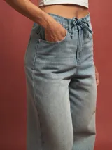 Pantalón de jean celeste de corte ancho, con cintura alta ajustable con cordón.