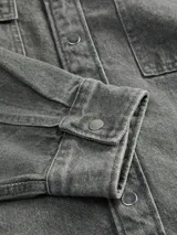 Sobrecamisa gris de denim con cuello con solapa, cierre con botones, dos bolsillos con solapa en el pecho y corte amplio.