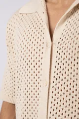 Camisa negra tejida de manga corta, con calado aireado, cuello tipo bowling y botones al tono. Diseño de corte relajado.