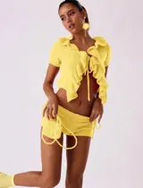 Conjunto amarillo tejido de punto, compuesto por un top de manga corta con volantes y un short mini con lazos laterales.