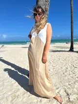 Vestido largo de tirantes, con corpiño en color blanco texturizado y falda larga en tono beige/dorado con brillo sutil. Presenta un escote en V profundo en el frente.