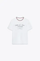 Camiseta blanca de algodón con cuello redondo y ribete tricot en rosa y verde. Estampado frontal con texto en color negro.