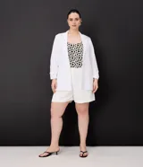 Bermuda de crepé color blanco, de corte holgado y tiro alto, con pliegues frontales y bolsillos laterales con detalle de botones. Confeccionada en poliéster y elastano.