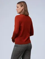 Polera de punto fino marca Nienty, color blanco, con cuello alto volcado y mangas largas con detalle de tajo en los puños.