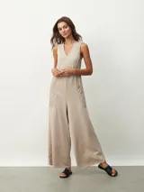 Mono largo color beige, de corte holgado, con cuello redondo y mangas cortas. Presenta bolsillos laterales y detalle de costuras verticales en el frente.