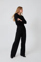 Cardigan negro de acrílico, ajustado al cuerpo, con cuello a la base, manga larga y cierre frontal con botones.