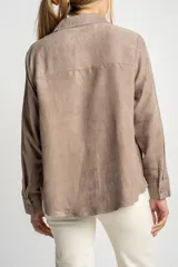 Camisa color marrón claro de gamuza vegana con calce oversize, cuello clásico, cierre frontal con botones y mangas largas con puños abotonados.