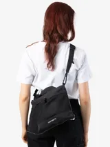 Bolso bandolera Carhartt WIP modelo Irwin, color negro. Cuenta con compartimento principal con cierre de cremallera, bolsillo lateral de malla, bolsillo frontal con cierre a presión, asa de mano y correa bandolera ajustable. Logo de la marca estampado en blanco en la parte inferior.