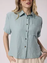 Camisa blanca de manga corta con cuello clásico y bolsillo en el pecho. Confeccionada en lino y viscosa.