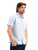 Camisa de manga corta color beige, confeccionada en 100% algodón, con cuello clásico, cierre frontal con botones y bolsillo en el pecho.