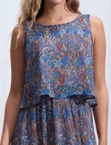 Vestido largo sin mangas de gasa estampada en tonos azules y marrones. Presenta escote redondo y corte en la cintura con punto smock.