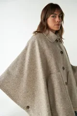 Capa con cuello, cierre frontal con botones y bolsillos delanteros. Confeccionada en lana fina sin teñir, diseñada exclusivamente por Don Baez.