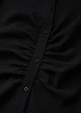 Vestido camisero midi negro con textura de mini rombos, corte entallado, cuello camisero, cierre frontal con botones, mangas largas abullonadas y frunces en la cintura.