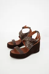 Sandalias negras con plataforma y taco de cuña, tiras de cuero con apliques de tachas plateadas y hebilla lateral.