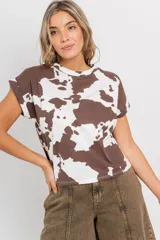 Remera de corte recto y oversize, confeccionada en algodón y elastano. Presenta un estampado de manchas de vaca en tonos marrón y blanco, y mangas con doblez en el borde.