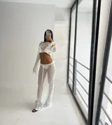 Conjunto de dos piezas de tejido de red (crochet) color blanco, compuesto por un top manga larga cropped y una falda larga ajustada con cordón de ajuste.