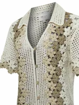 Sweater tejido a crochet color crema con flores bordadas en tonos beige y marrón. Tiene cuello camisero, mangas cortas y cierre frontal con botones.