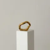 Anillo dorado de acero quirúrgico hipoalergénico con baño en oro 18K, de forma irregular.