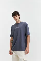 Remera color crudo de corte amplio, con mangas cortas y estampado en la espalda con flores rojas y texto en negro.