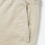 Bermuda color beige con textura tipo waffle, de corte recto y largo a la rodilla. Cuenta con cintura elástica y cordón ajustable.