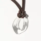 Colgante con cordón marrón de gamuza sintética y dije circular transparente.