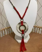 Collar largo con cadena de eslabones color bronce, cordón rojo, dije circular de nácar con aro dorado y borla de flecos rojos.