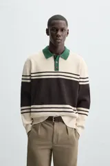 Polo de hombre relaxed fit, tejido en hilatura con textura chenilla. Presenta cuello solapa con cierre frontal de botonadura, manga larga y acabados en rib. Diseño a rayas horizontales en color crema y negro, con cuello en verde oscuro.
