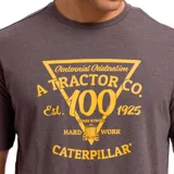 Remera gris de hombre con estampado amarillo en el pecho con el logo de Caterpillar y la leyenda "Centennial Celebration A Tractor Co. Est. 1925 Hard Work Caterpillar".