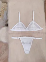 Conjunto de lencería blanco de microtul suave y elastizado con detalles de encaje. Incluye corpiño triangular y tanga regulable de elástico ancho con entrepierna de algodón.