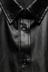 Sobrecamisa negra de efecto piel, con cuello de solapa, manga larga con puños abotonados, bajo recto y cierre frontal con botones.