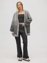 Cardigan tejido de punto con patrón de rombos en degradé de grises y blanco. Tiene corte oversize, mangas largas y cierre frontal con botones.