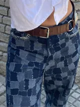 Pantalón de jean ancho (wide leg) de algodón, con diseño de patchwork en tonos de azul que simula un patrón a cuadros, con bordados artesanales a mano en las costuras.