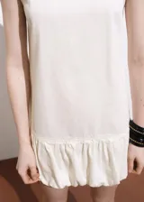 Vestido corto sin mangas de algodón estilo tejano vaquero, color blanco, con cuello redondo y bajo abullonado.