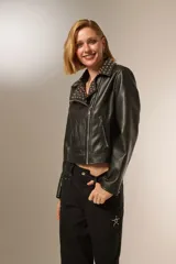 Chaqueta corta de cuero sintético negro con cuello solapa con tachas plateadas, cierre cruzado con cremallera, bolsillos con cremallera y corte holgado.