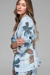 Conjunto de dos piezas compuesto por un blazer de manga larga y un pantalón palazzo de pierna ancha. Ambas prendas son de tela liviana y presentan un estampado floral en tonos celestes, azules y marrones sobre fondo celeste claro. El blazer tiene solapas y bolsillos frontales.