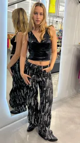Pantalón de jean negro con estampado abstracto en gris, corte wide leg y tiro alto.