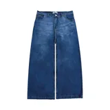Pantalón de denim azul desgastado, corte mega baggy con bolsillos grandes y botones personalizados.