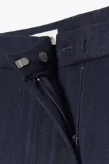 Pantalón de vestir azul marino, de tiro medio, con bolsillos delanteros y falsos bolsillos de vivo en la espalda. Pierna recta y acampanada.