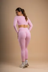 Conjunto deportivo color beige compuesto por calza de tiro alto y top de manga larga con escote cuadrado y logo bordado en el pecho.
