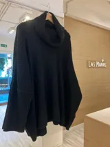 Sweater verde oscuro tejido con cuello alto volcado y mangas largas amplias.
