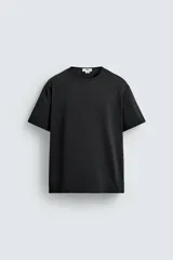 Camiseta negra de corte relaxed fit, confeccionada en tejido compacto de algodón. Tiene cuello redondo con ribete doble y mangas cortas.