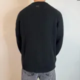 Sweater negro de tejido de punto grueso, con cuello alto y mangas raglán. Corte holgado.