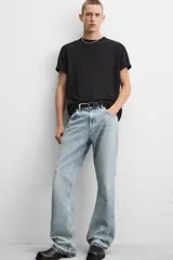 Pantalón de jean negro con efecto lavado, corte flare, cinco bolsillos, cierre frontal con cremallera y botón, y bajo con acabado irregular.