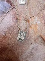 Cadena dorada con dije rectangular con imagen religiosa.