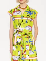 Vestido camisero midi color verde lima con estampado de cisnes, flores y elementos abstractos. Tiene cuello camisero, mangas cortas, cierre frontal con botones y lazo en la cintura. La falda es amplia con volantes en el ruedo.