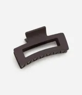 Pinza para el pelo rectangular color marrón oscuro, de plástico gomoso con abertura rectangular en el centro.