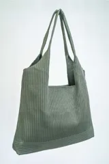 Bolso negro tipo tote bag con textura acanalada y asas de hombro.