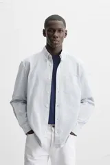 Camisa azul marino de corte regular fit, confeccionada en tejido de algodón Oxford. Tiene cuello abotonado, manga larga con puños abotonados, bolsillo de parche en el pecho y cierre frontal con botones.